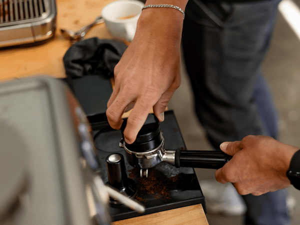 Teilnehmer des Barista Kurses übt Tampern des Kaffeemehls.