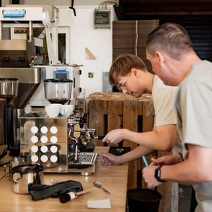 Teilnehmer lernen beim Barista Kurs für Firmen und Teams, wie man Espresso zubereitet.