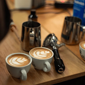 Teilnehmer üben das Gießen einer Tulpe im Latte Art Workshop