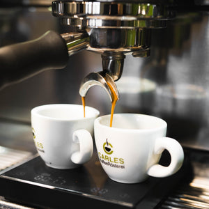 Frisch extrahierter Espresso läuft während des Barista Kurses aus der Siebträgermaschine in die Tassen.
